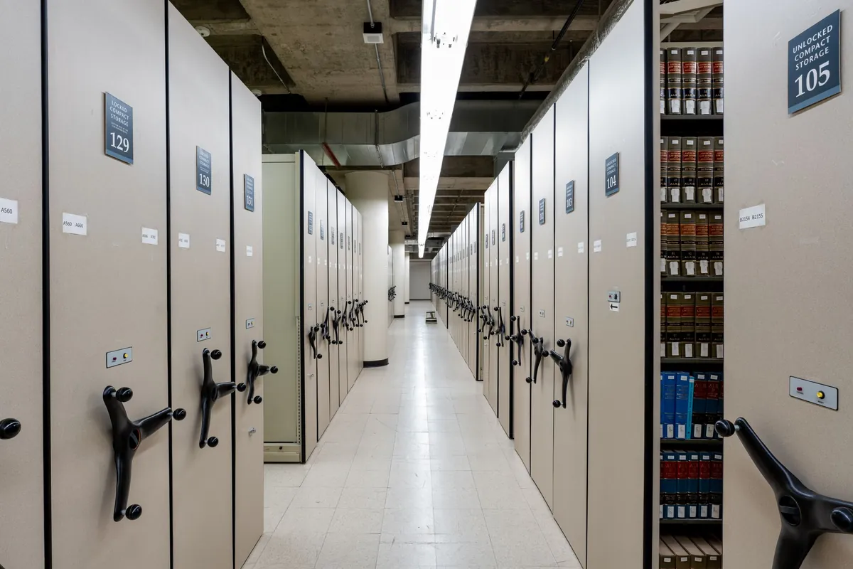 Rows of high-density mobile filing units with rotary handles in a records storage room