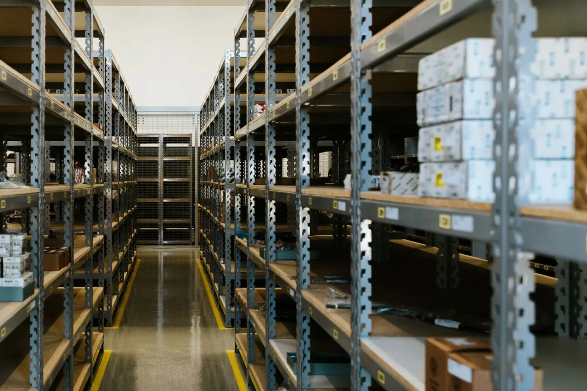 Gray steel shelving units with boxed inventory along a stockroom aisle